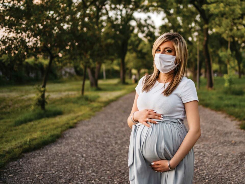 Pregnant woman outdoors wearing a mask