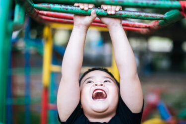 kid handing from monkey bars at a gym