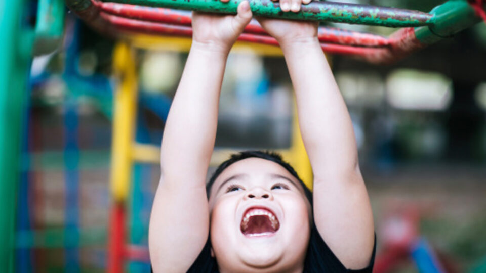 kid handing from monkey bars at a gym